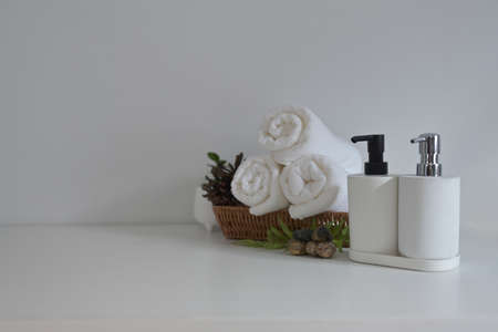 Panoramic view of clean rolled towels in wicker basket putting on white table with a modern white...
