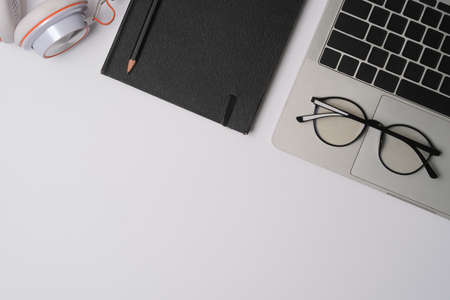 Top view white modern desk surrounded by computer laptop, notebook, glasses, and headphone.の写真素材