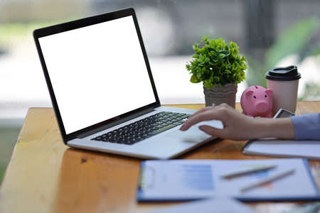 Cropped image of a young accountant is using a white blank screen computer laptop at the wooden working table.の写真素材