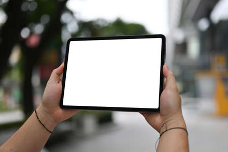 Cropped image of the hand using a white blank screen digital tablet in the park.