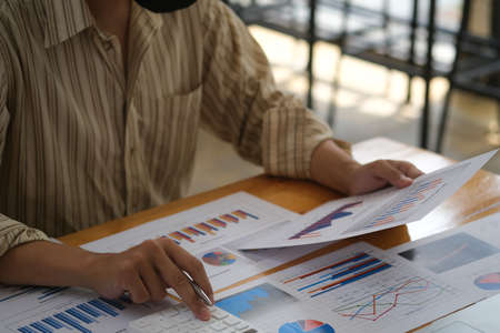 Closed up with young accountant calculating annual balance sheet at the busy working desk.