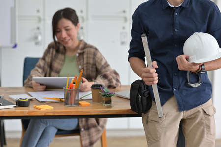 Photo of an architect man standing over the office surrounded by architect woman is working at the...