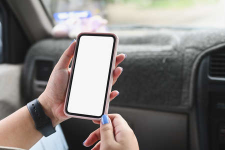 Close up image of a young woman using a white blank screen smartphone while sitting in the passenger...