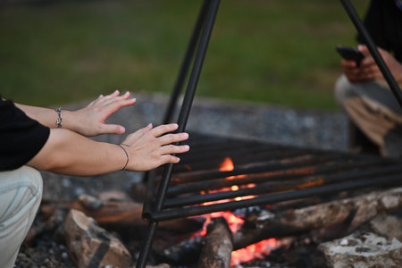 Closed up with a group of cheerful happy friends sitting at the bonfire for making warm. Outdoors activity, Hiking, Camping, Picnic concept.の写真素材