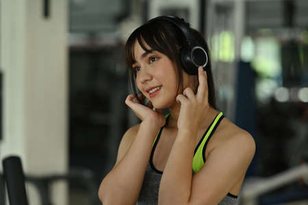 Closed up with beautiful sporty girl listening to music while doing an exercise in the comfortable gym.の写真素材