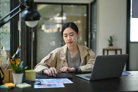 Photo of a young designer woman working with a computer laptop at a comfortable workplace.の写真素材