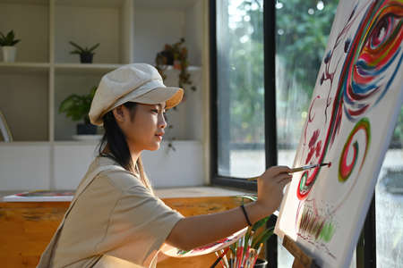Photo of an adorable girl painting on drawing canvas in the modern art studio.の写真素材