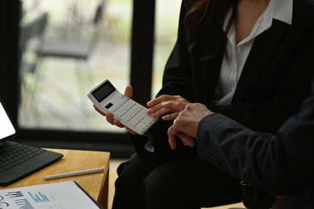 Cropped image of an insurance agent calculates an insurance program and showing to the elderly customer at the comfortable chair.の写真素材