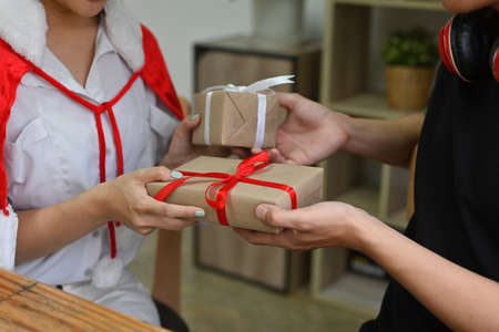 Photo of a lovely couple giving each other Christmas presents box in the comfortable living room.の写真素材