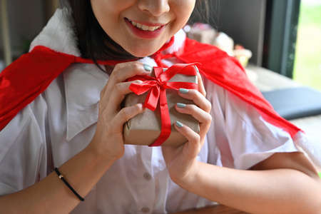 Cropped image of a beautiful woman holding a Christmas present box at the wooden table in the comfortable living room.の写真素材