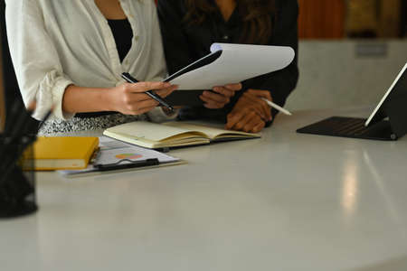 Cropped image of two designers making a conference at the white table surrounded by a digital...