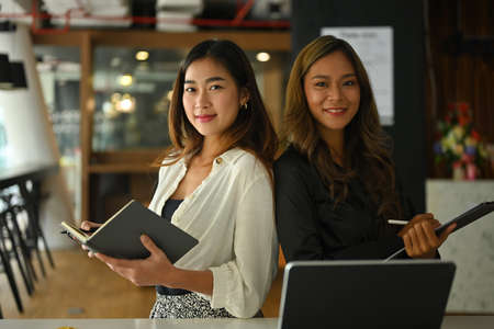 Photo of a beautiful businesswoman standing with leaning each other back over the modern office as a...