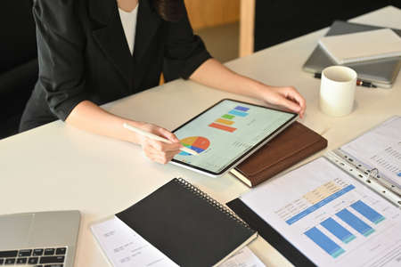 Top view image of businesswoman hand using a stylus pen and digital tablet with graphic charts on...