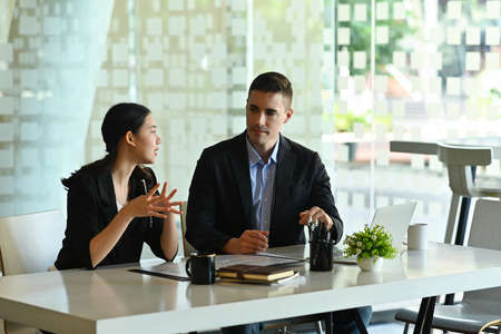 Photo of businesspeople working together at the modern office desk with the comfortable meeting room as a background.の写真素材