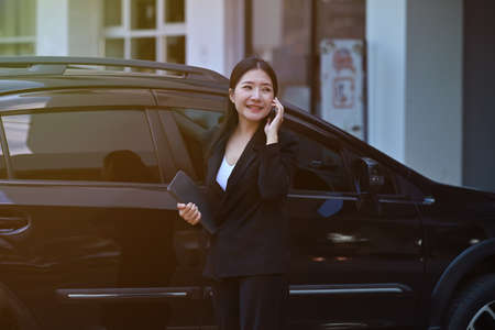 Photo of an insurance agent talking on mobile phone while standing with the digital tablet over a...