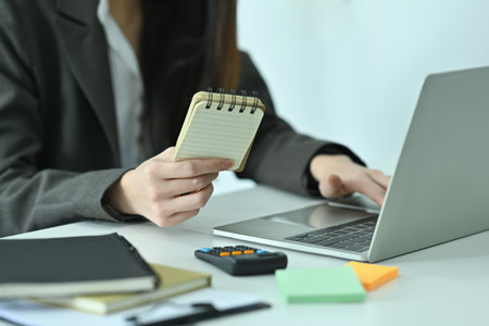 Cropped image of a businesswoman checking a company expense at the modern working desk surrounded by...