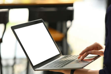 Cropped image of the office girl standing with using a white blank screen computer laptop on hand.