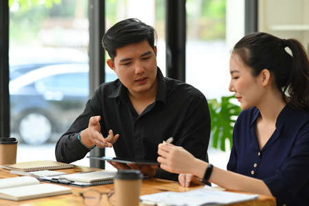 Photo of a young business development team working together at the wooden working desk surrounded by...