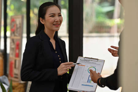 Photo of a businesswoman standing and showing business graphic charts in the modern office.