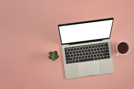 Top view with modern laptop with cup of coffee on pink studio background, copy space and work place, empty screen of laptop.の写真素材