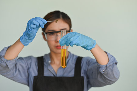 Selective focus of Scientist or Researcher's hands dropping dried cannabis flowers into a test tube,...