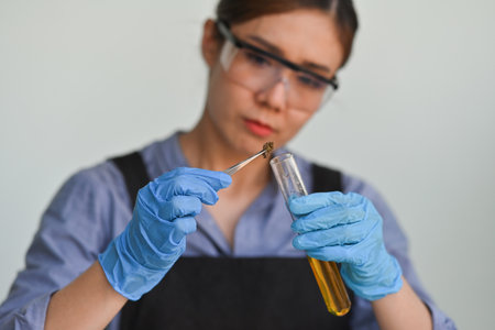 Selective focus of Scientist or Researcher's hands dropping dried cannabis flowers into a test tube, Cannabis study process, Legal use of marijuana for medical and recreation.の写真素材