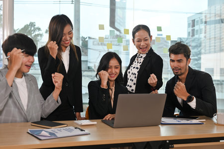 Middle-aged woman team leader and her team screaming with joy and celebrating by victory pose, Celebrating business success make great deal, great results, growth of sales concept.の写真素材