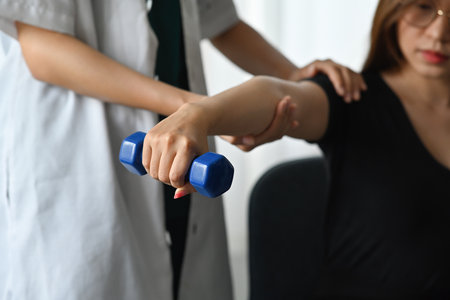 Focused on Asian woman training with physical therapist by using dumbbell.
