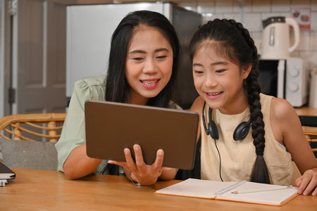 Portrait image of Mom and daughter using tablet for online learning, Coronavirus pandemic forces...