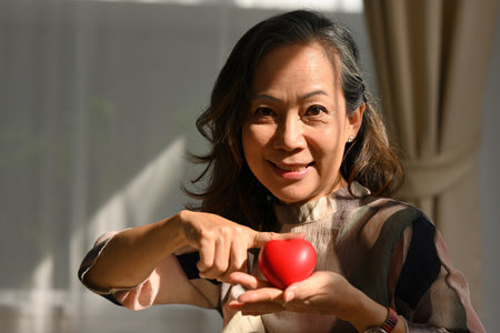 Happy old aged woman holding heart model, Health insurance and Insurance premium for senior people,...