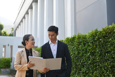 Old senior businesswoman showing document data to her colleague while both moving after work.の写真素材
