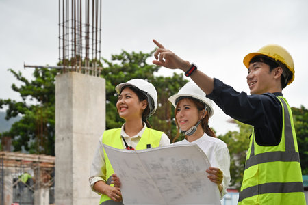 Civil engineers and foreman in helmet and vest checking a building project on the construction site.