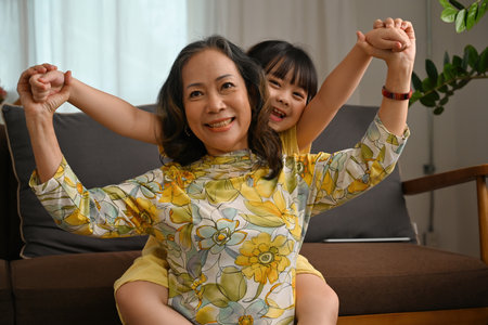 Small happy girl ride on back her grandmother, Elderly with grandchildren concept.の写真素材