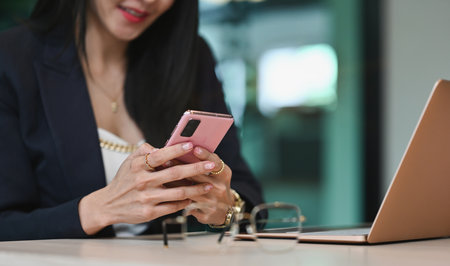 Cropped shot of businesswoman using smart phone at her workstation.の写真素材