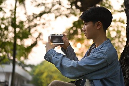 Portrait of Young Asian man using camera take a picture, hobbies, travel and nature concept.の写真素材
