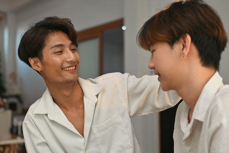 Young gay boy with Asian colored skin gently stroking his boyfriend's head with love and affection,...