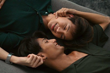 Top view with Young Asian gay couple lying on sofa and looking into each other romantically.の写真素材