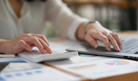 Close up image of a young businesswoman or accountant pressing a calculator to make financial...