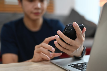 Close up and cropped image of Young Asian man using smartphone at home.