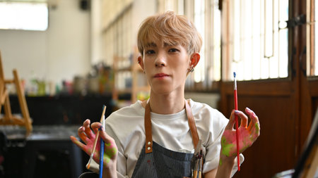 Portrait of a young LGBT artist with colored hair posing playfully in the workshop studio..