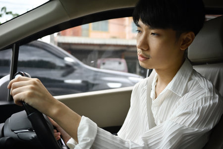 A shot from inside a car with a sleepy-looking Asian man driving a car. falling asleep while...