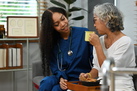An African Female caregiver serving food to the senior woman in the nursing home. Caring for the elderly people and nursing homes concepts.の写真素材