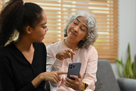 Young African daughter-in-law explains to grandmother how to use a smartphone or some applications...