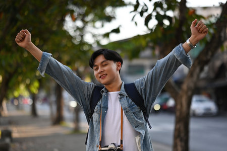 Handsome Asian male traveler with his backpack walking around the city Breathe in the fresh air of...