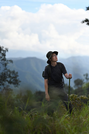 Portrait with Asian adventurer man hiking with a backpack on top of the mountain, A Solo travel...