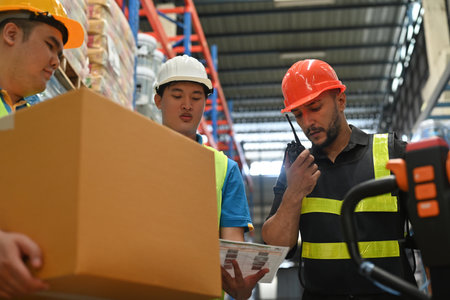 Warehouse worker Caucasian man with team using walkie talkie radio to control stock and inventory in retail warehouse logistics, distribution center.の写真素材