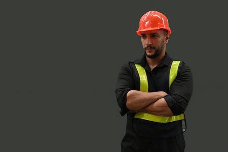 Portrait studio shot of a professional Caucasian man in an orange hard helmet and reflective safety vest, who is a welder or maintenance technician on color background.の写真素材