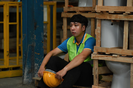 Young Asian worker feeling tired from hard work in a warehouse, Being fired from work, Unemployed, Failed, Hopeless, and Burned out at work concepts.の写真素材