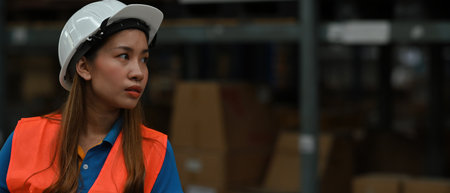 Portrait of stressed and Tired female worker wearing a safety hard hat helmet at warehouse manufacturing, panorama banner.の写真素材