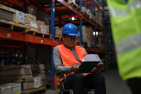 Senior manager with disability in a wheelchair checks stock work at warehouse, the concept of workers with disabilities, accessible workplace for employees with mobility impairment.の写真素材